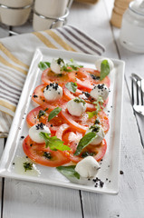 Caprese salad with tomatoes, mozzarella cheese and fresh basil leaves.