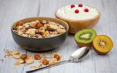 Bio Fruit Blueberry in bowl wood and Natural yogurt, kiwi, Raspberry, and nuts for health and diet with vitamin c in close-up on the wood table.