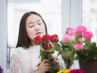 Woman Preparing to trim red and pink roses and beautiful flower arrangements in the home, flower arrangements with vase for gift-giving for Valentine's Day and Business in the family on the on table