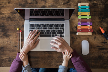 Stay at home working concept. Father trying to work from home with his son.