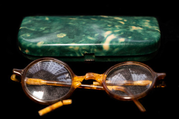 Broken old glasses on a black background with a case