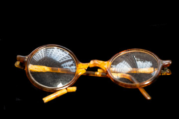 Broken old glasses on a black background