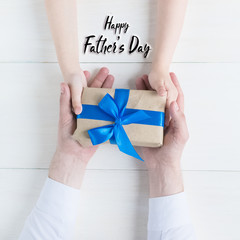 Happy father's day.Greeting card.Gift in the hands of daughter and father on a white background.I...