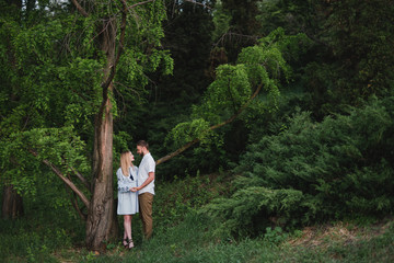 Naklejka na ściany i meble Romantic and happy caucasian couple in casual clothes hugging on the background of beautiful nature. Love, relationships, romance, happiness concept. Man and woman walking outdoors together.