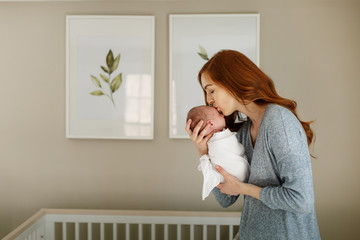 Mom kissing her newborn son in nursery