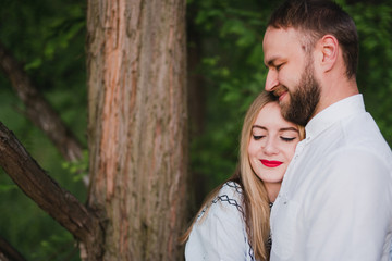 Romantic and happy caucasian couple in casual clothes hugging on the background of beautiful nature. Love, relationships, romance, happiness concept. Man and woman walking outdoors together.