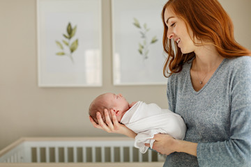Mother holding newborn baby in nursery