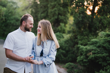 Fototapeta premium Romantic and happy caucasian couple in casual clothes hugging on the background of beautiful nature. Love, relationships, romance, happiness concept. Man and woman walking outdoors together.