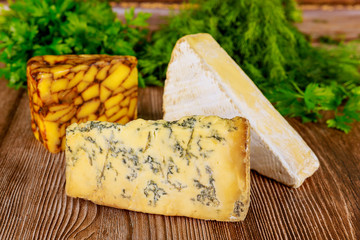 Different types of cheese with herb on wooden background.