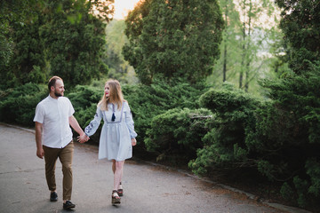 Fototapeta premium Romantic and happy caucasian couple in casual clothes hugging on the background of beautiful nature. Love, relationships, romance, happiness concept. Man and woman walking outdoors together.