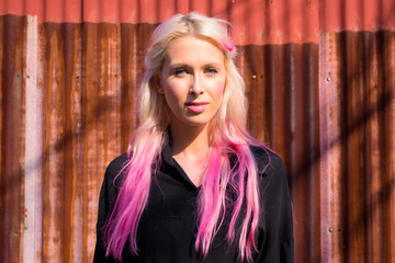 Face of young beautiful blonde woman against rusty iron wall