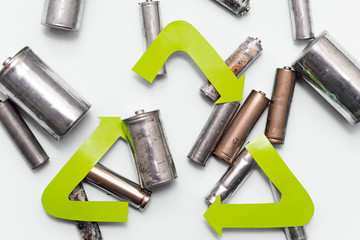 Use AA and properly dispose of batteries that are toxic to the environment and soil against a green background. The concept of technologies for processing hazardous and recyclable substances.