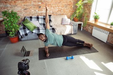 African-american man teaching at home online courses of fitness, aerobic, sporty lifestyle while...
