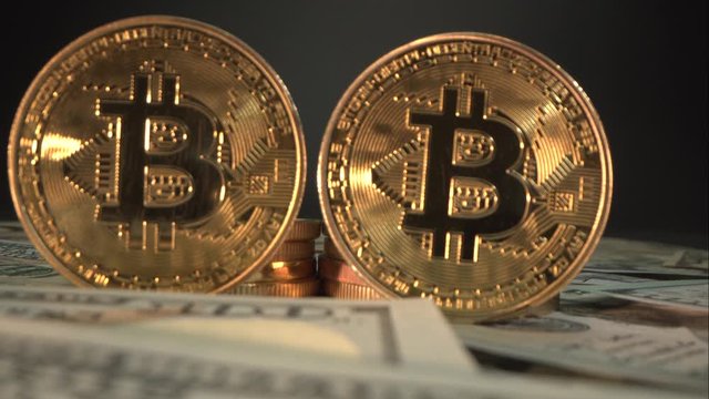 Camera move bake from two golden bitcoins on the table with many dollar bills and fantastic light on it. Super Macro shot. 4K video. Before halving. Behind of BTC are another bitcoins. Cryptocurrency