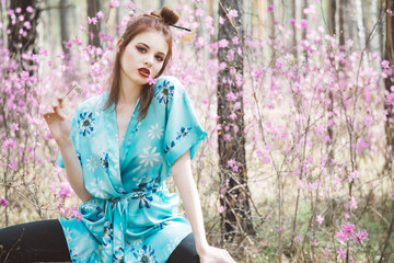 A girl dressed in Japanese style in a flowering forest among pink flowers