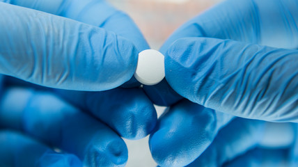 A medical scientist is holding a pill from the covid-19 virus in his hands.