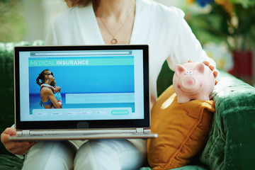 woman with piggy bank showing laptop with medical insurance site