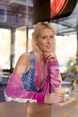 Happy young beautiful blonde woman sitting at the coffee shop