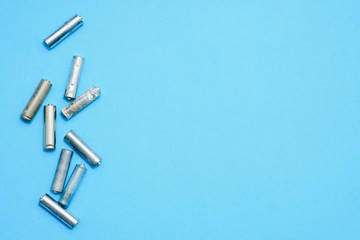 Scattered old dirty batteries aa or aaa size on blue background. Recycling concept. Save environment. Alternative energy