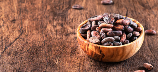Unpeeled cocoa bean on wooden rustic background, close-up. Copy space