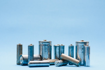 many used AA batteries on a blue background.