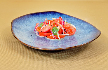 Salad with tomatoes and kujut on a blue plate