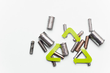 waste recycling, garbage disposal, environment and ecology concept - close up of used alkaline batteries and green recycling symbol