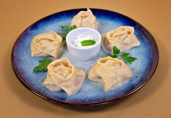 Uzbek manti on a blue plate with cream sauce
