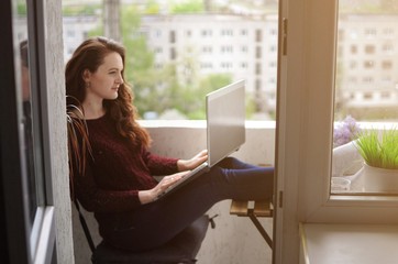 Woman freelancer working on a laptop on balcony during corona virus quarantine