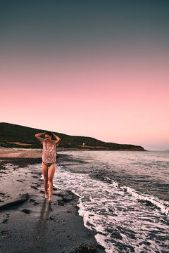 solitary girl walking on tamarone beach at the sunset, corse mediterranean france