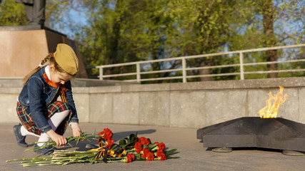 Little Girl Laying Flowers to Eternal flame Memorial. Russian Victory Day.  Second World War Victory