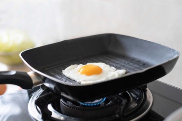 fried egg in a hot frying pan on a gas stove