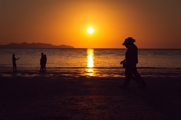 people walking on beach at sunset