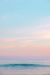Expanse of the ocean against the sunset sky. Gorgeous pink, lilac sunset over the quiet expanse of the sea with wave. Fantastic seascape. Natural composition.