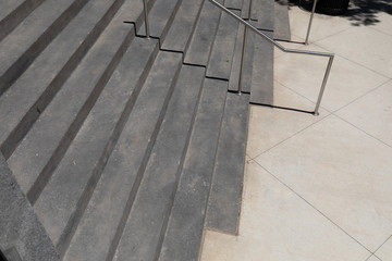View across a wide gray concrete staircase, urban outdoor city scene, metal railings and concrete sidewalk, horizontal aspect
