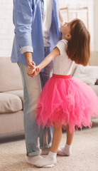 Little princess standing on father feet and dancing