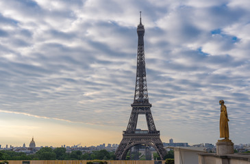 Paris, France - 05 06 2020: Golden statue of a woman wearing a surgical mask during confinement against coronavirus and the eiffel tower