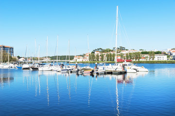 Fototapeta na wymiar white yachts and boats stand near the pier in a small European city in the summer, a luxury vacation for wealthy people, a picturesque landscape