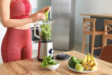 Sporty woman making smoothie in kitchen at home