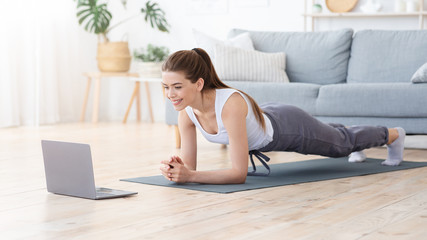 Obraz premium Positive girl planking at home, doing morning exercise