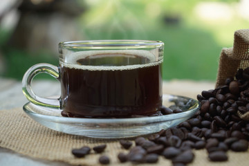 Hot Coffee cup and coffee beans roating on the wooden table