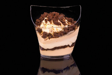 Tasty dessert with cookies oreo in a glass with reflection, isolated on black background.