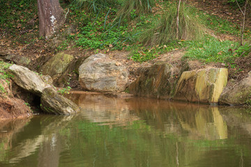 Naklejka na ściany i meble Bucolic scenery with lake, rocks, trees and green