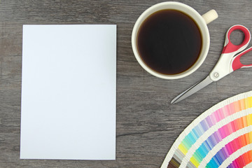 Top view of empty white page, elegant pencil, color range cards, scissors and coffee cup