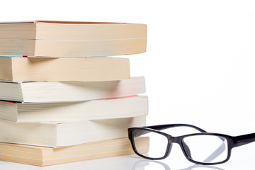 reading glasses and stacked books isolated on a white background