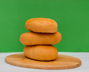 Baked pies on a wooden board on a green background. Food photo, copy space. Still life.