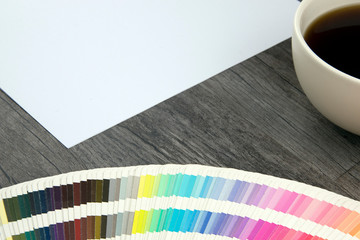 Close-up of empty white page and designers color range with coffee cup