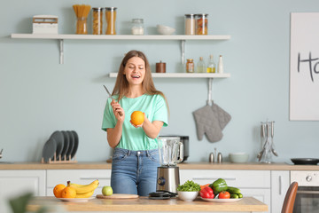 Young woman making smoothie in kitchen at home