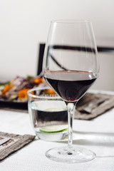 Photo of a home cozy supper with glass of red wine and salad from fresh eco vegetables on black plate indoors
