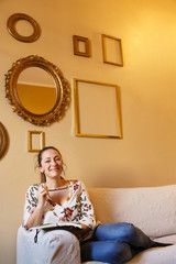 ragazza con i cappelli  raccolti sorride seduta comoda su un divano con un agenda in mano, isolata...